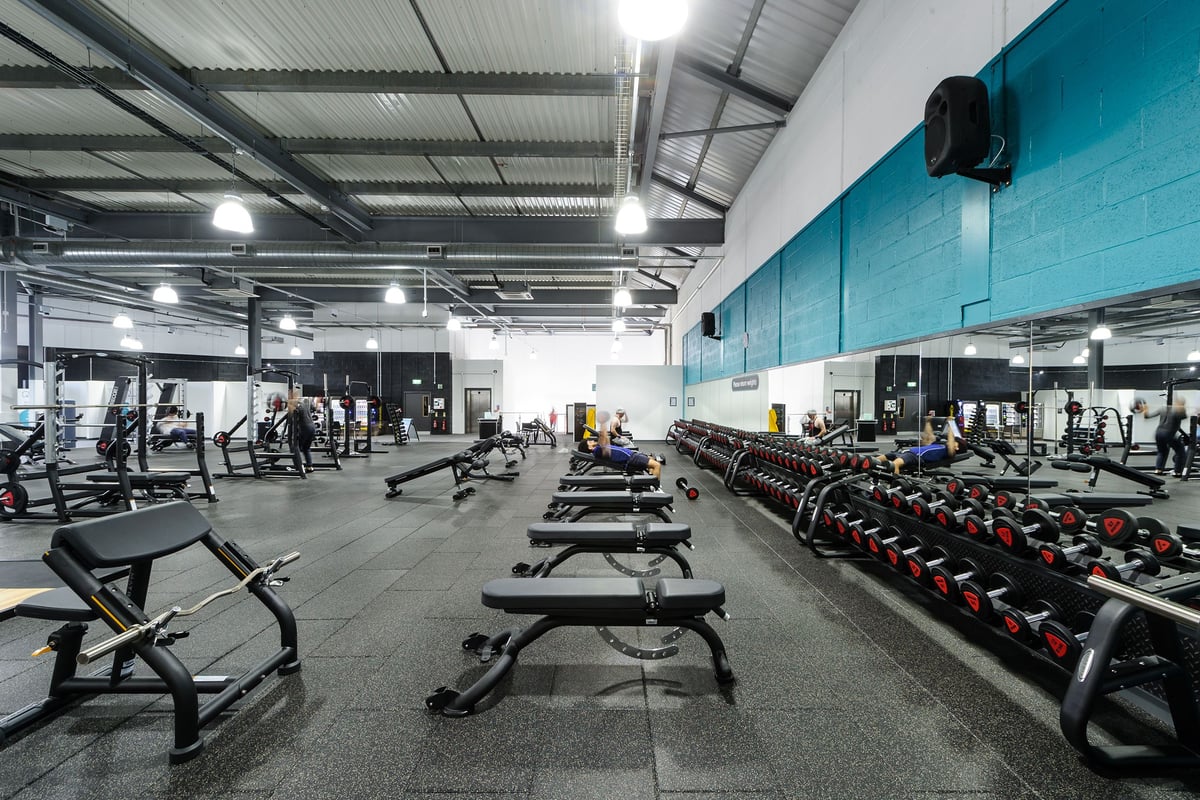 PureGym Worcester: Weight benches, free weights, weight racks, and rubberized flooring in a gym setting.