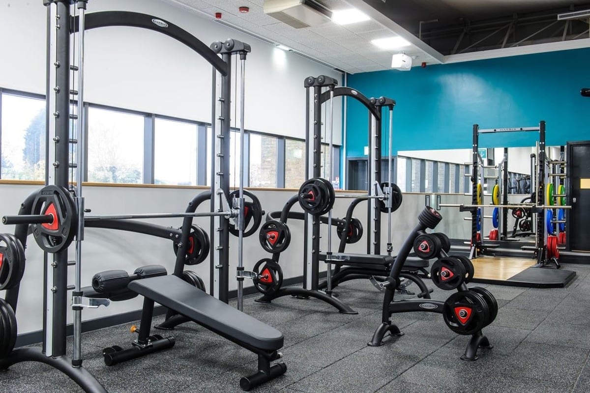 PureGym Bedford Heights: Squat racks, weight benches, free weights, and open floor space with rubberized flooring.