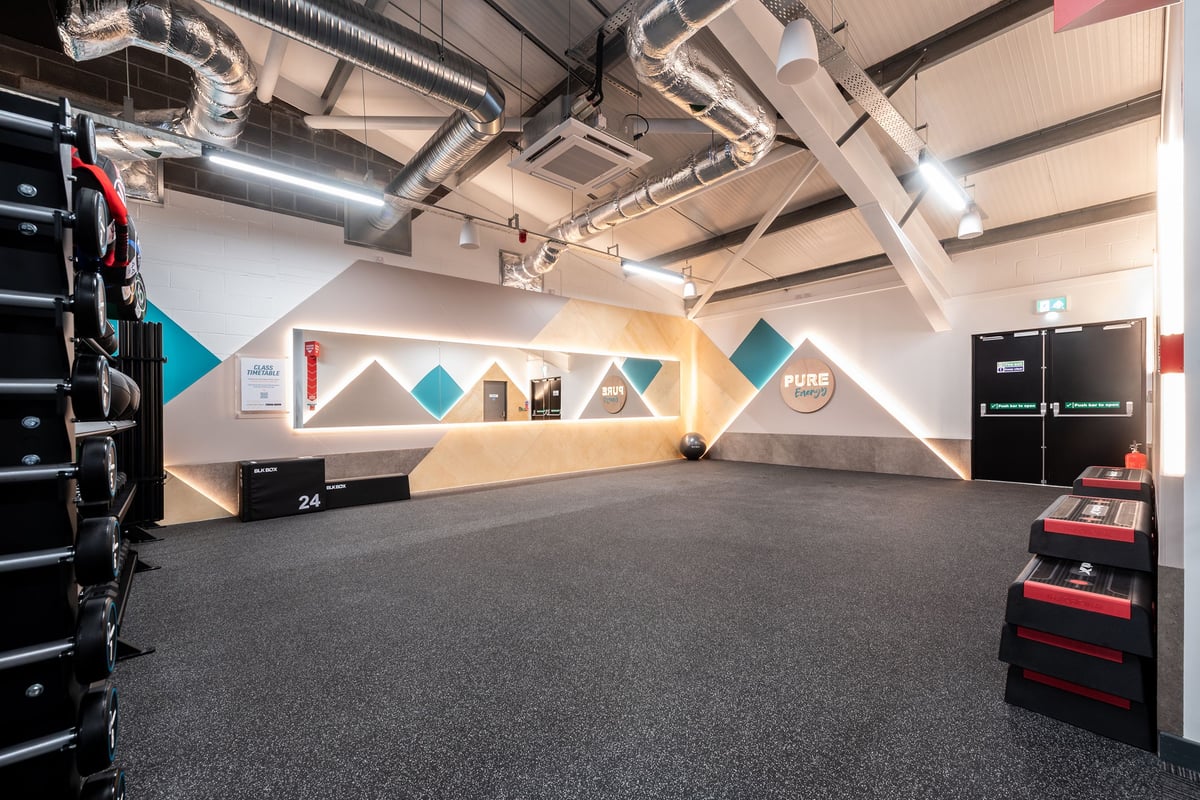 PureGym Aberdare: Rubberized flooring, angular geometric wall designs, free weights, and mirrored surfaces.