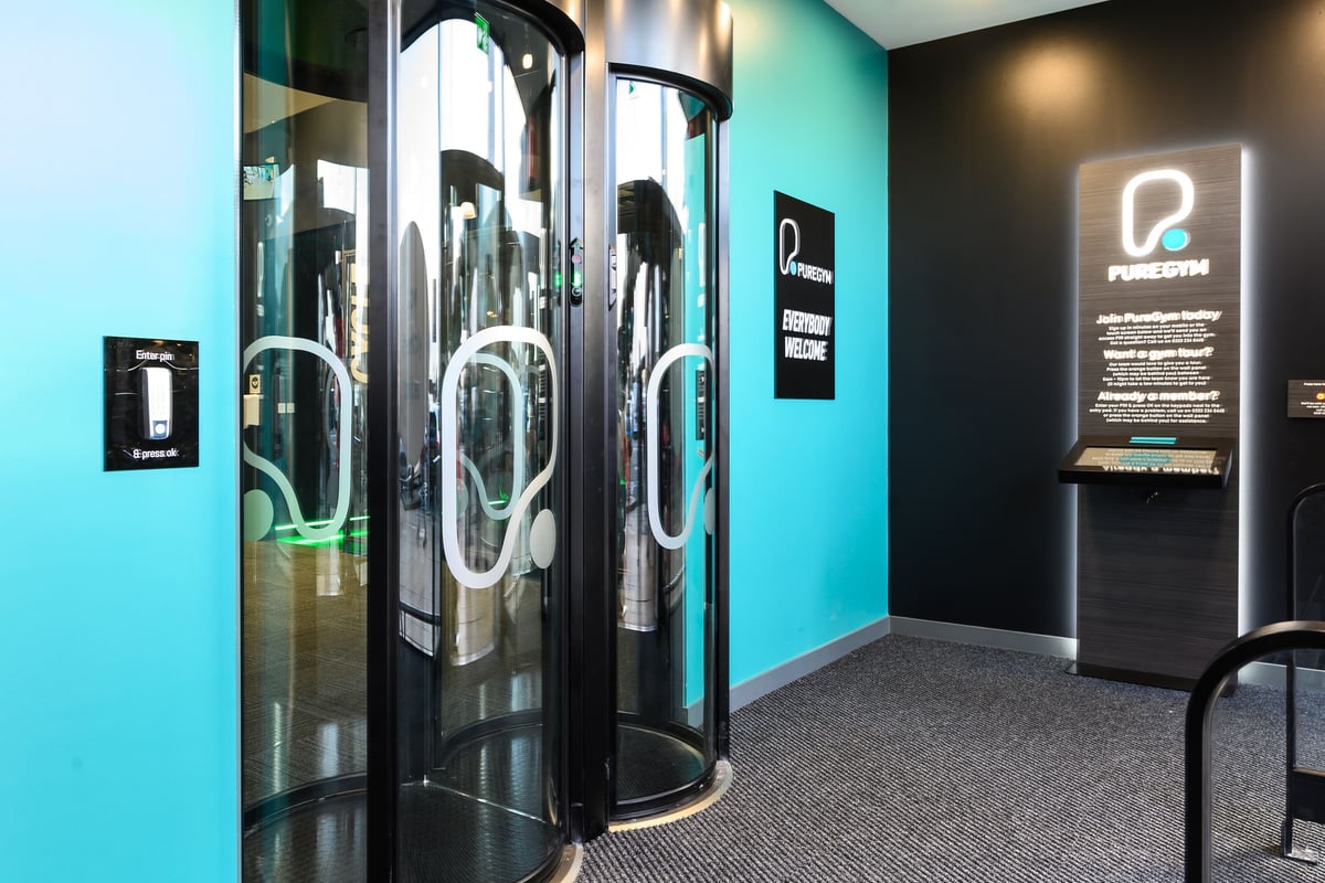 PureGym Romford: Rows of futuristic-looking fitness pods or capsules with neon teal lighting.