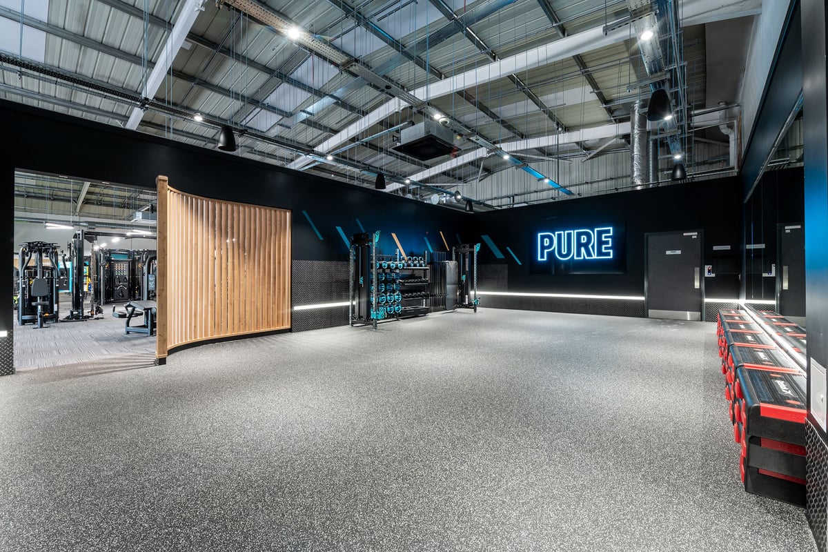PureGym Horsham: Weight racks, free weights, padded floor, wood feature wall inside a modern gym studio.