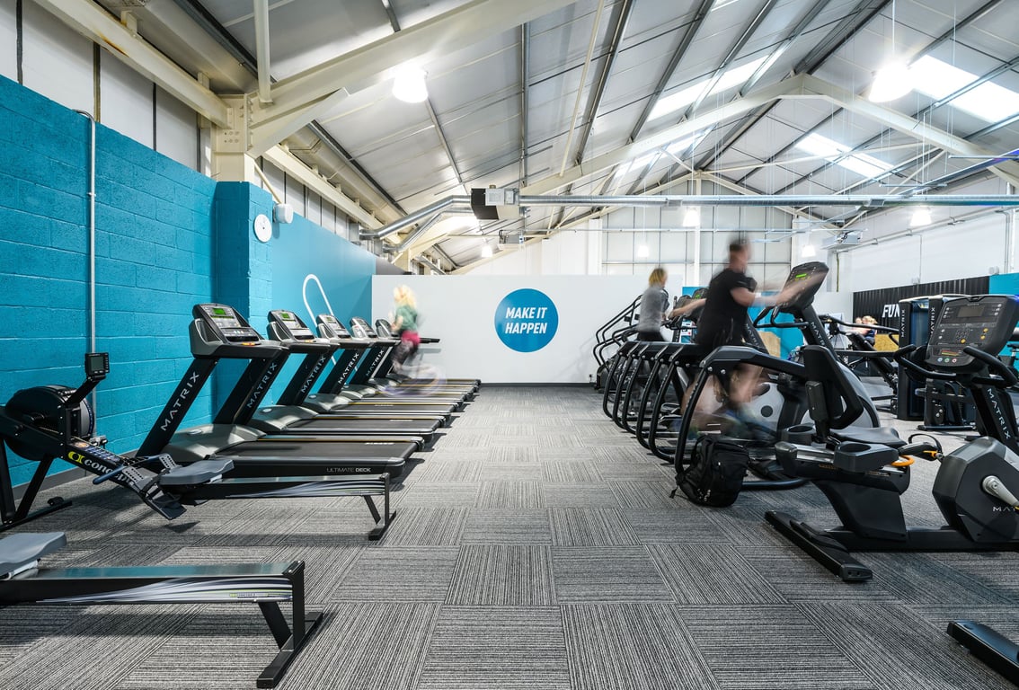 PureGym Bridgwater: Rows of treadmills, exercise bikes, and weight benches in a brightly lit fitness studio.