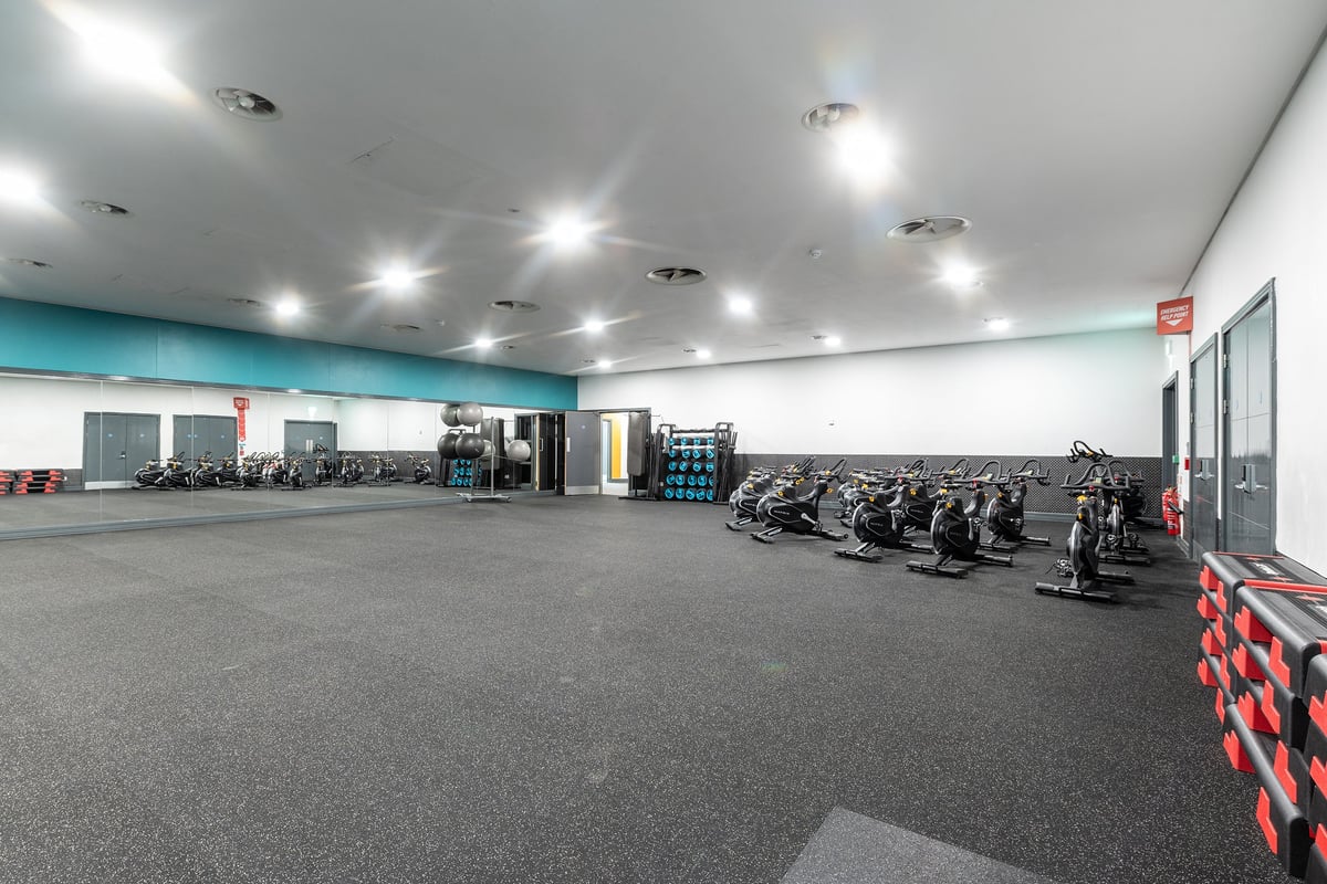 PureGym Bradford Thornbury: Rows of stationary bikes, treadmills, rubberized flooring, and mirrored walls inside a gym space.