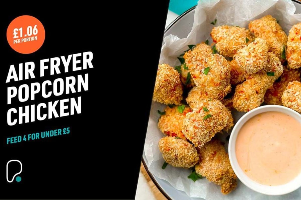 Breaded popcorn chicken pieces with dipping sauce on a plate with herbs