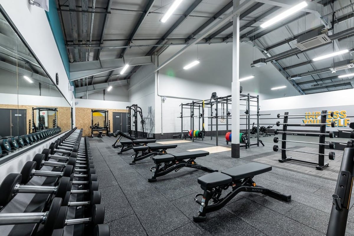 PureGym Uttoxeter: Weightlifting racks, benches, dumbbells, weight plates, and rubberized flooring in a gym setting.