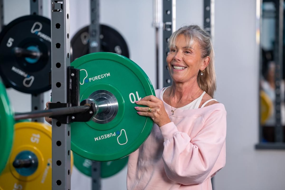 PureGym member smiling while taking a weight off a barbell