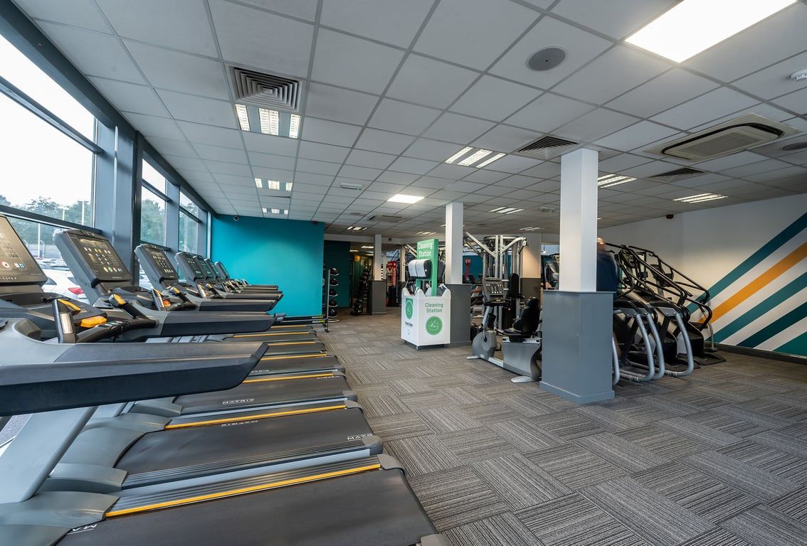 PureGym Rochdale: Rows of treadmills, weight machines, benches, and mirrored walls in a bright gym interior.