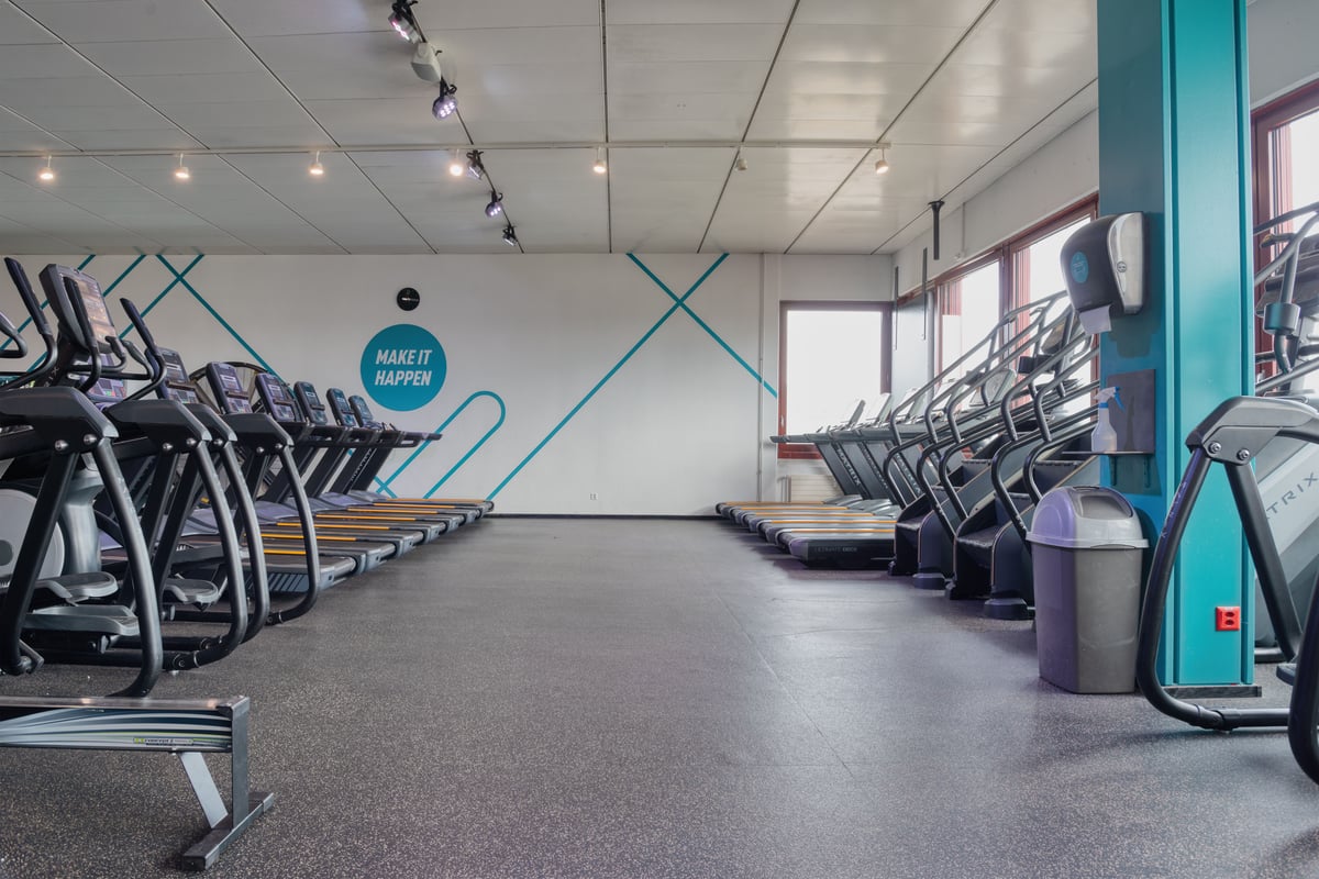 Salle cardio du gym avec tapis de course et vélos elliptiques