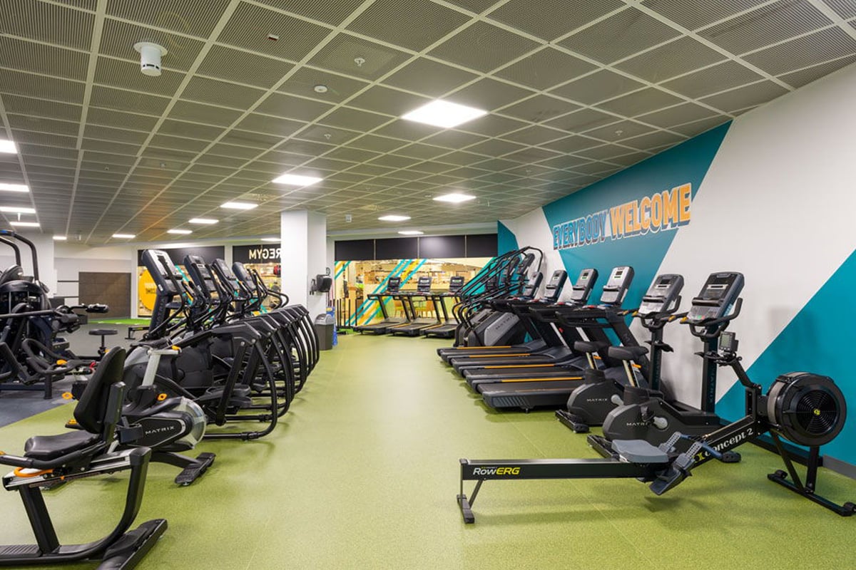 PureGym Lausanne Prilly: Rows of cardio machines like treadmills and ellipticals inside a gym with bright lighting.