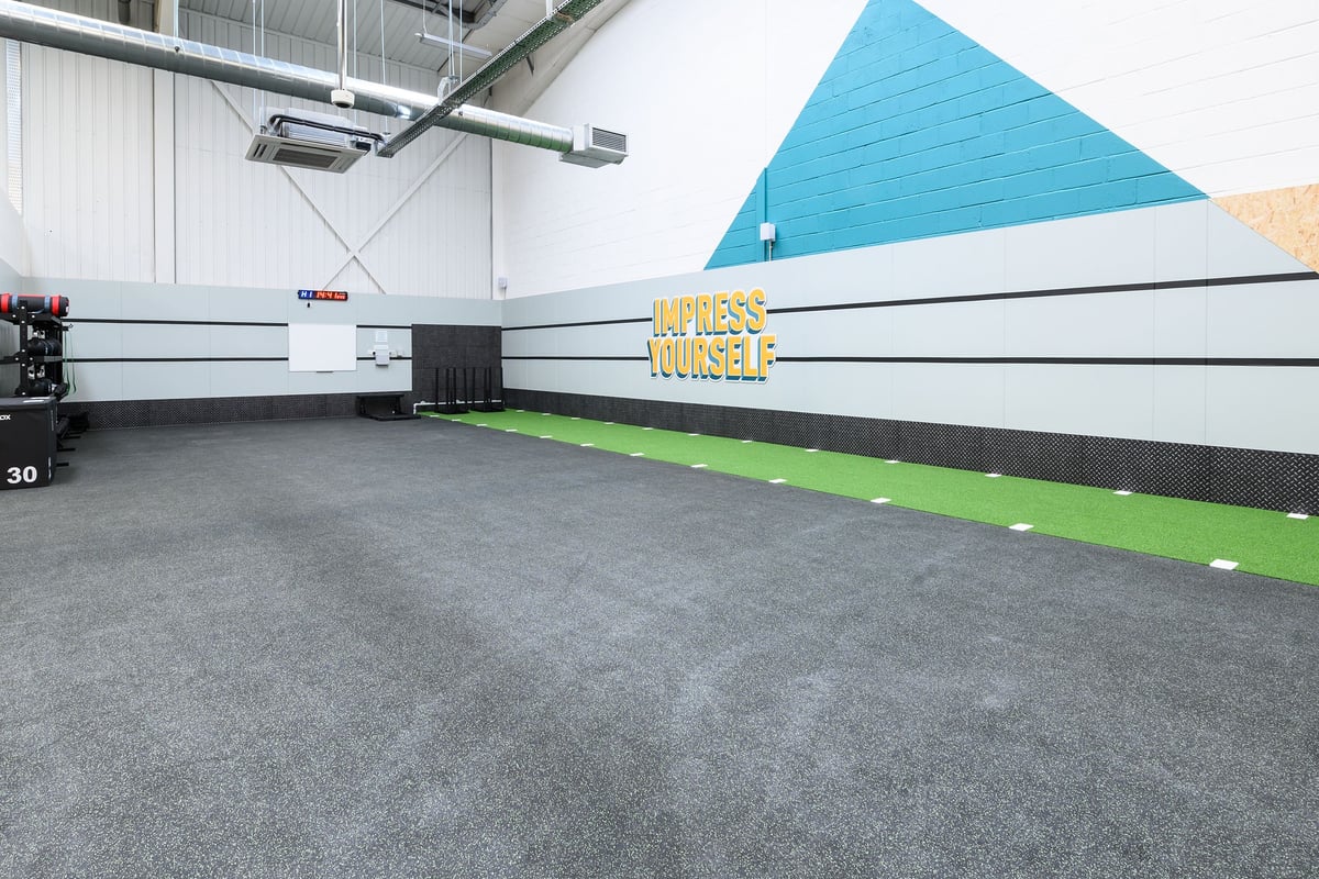 PureGym South Ruislip: Resistance tubing, rubberized flooring, geometric wall art, and brightly coloured accent lines.