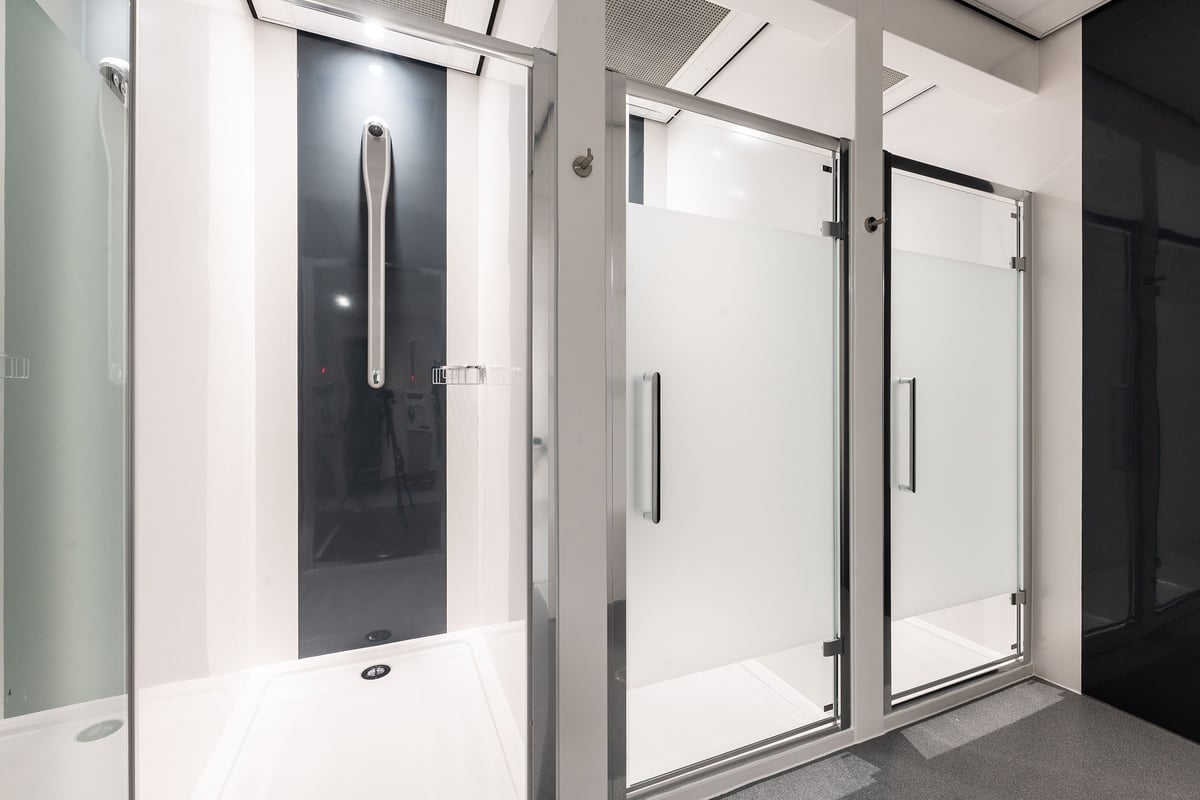 PureGym London Feltham: Shower cubicles with frosted glass doors, tiled floors.