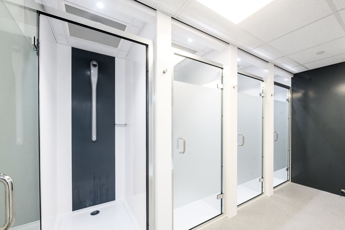 PureGym London Lambeth: Rows of shower stalls with frosted glass doors and privacy curtains.