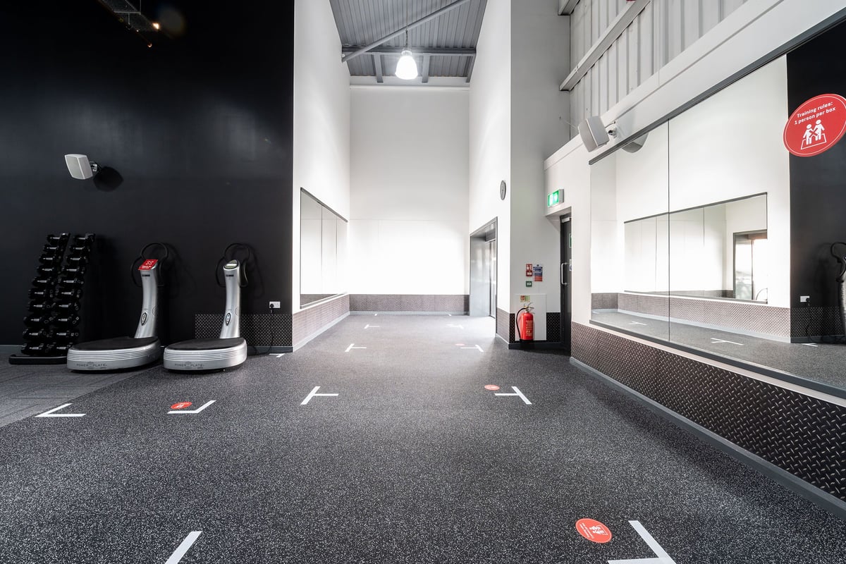 PureGym Warrington Central: Rows of automated vacuum cleaners, weight plates, and rubberized flooring inside a gym.