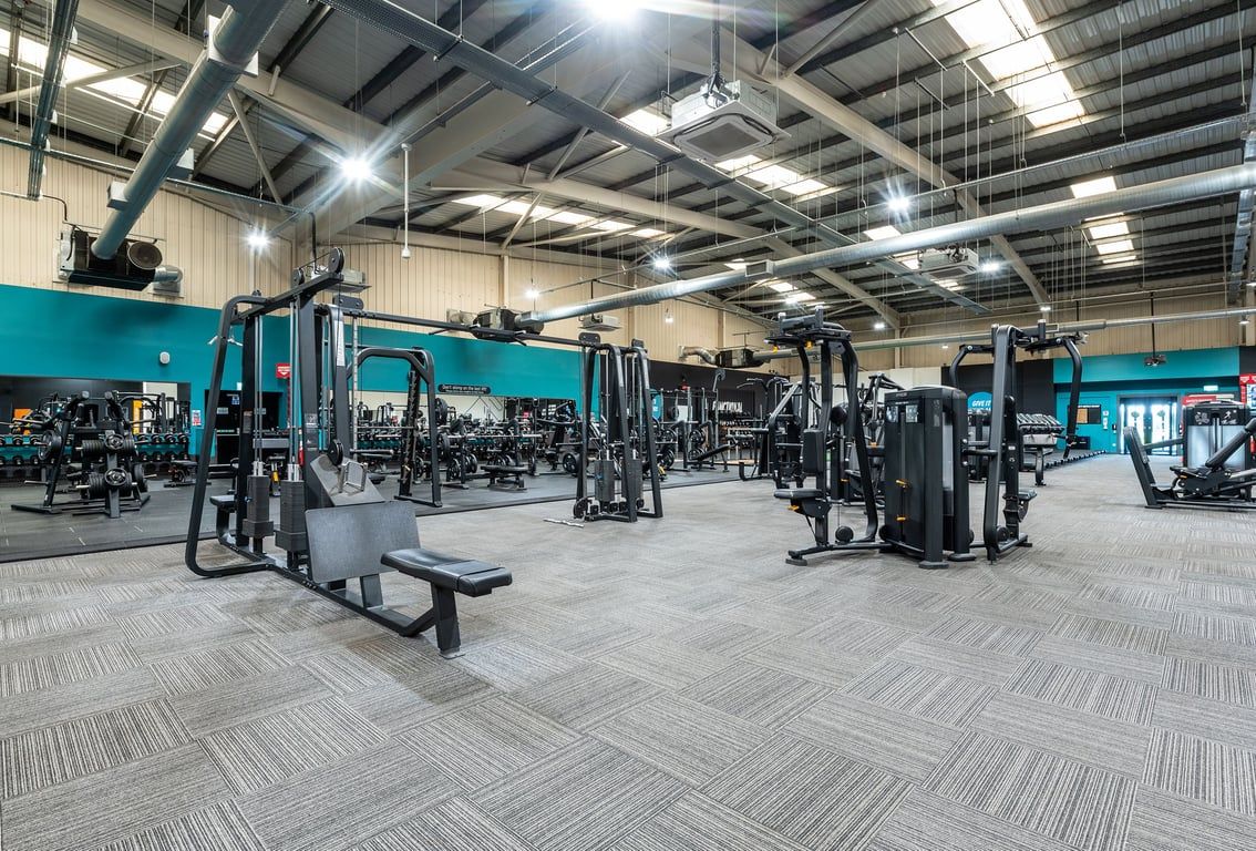 PureGym Weston-super-mare: Strength training equipment like cable machines, squat racks and benches on rubberized flooring.