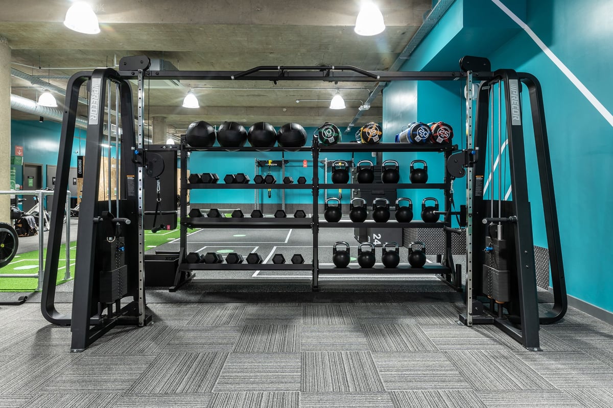 PureGym London Leytonstone: Free weight racks, resistance machines, rubberized flooring in a teal-colored gym studio.