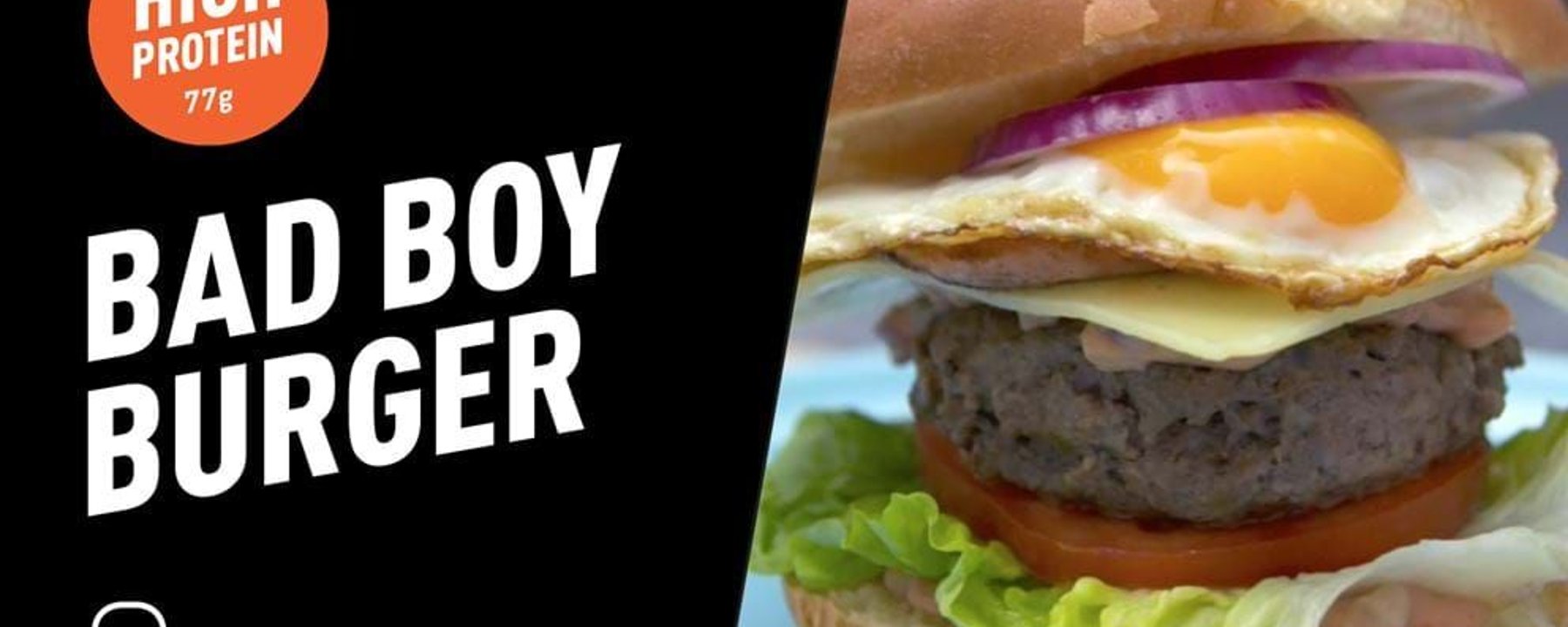 Burger with fried egg, cheese, tomato, lettuce, and red onion in a bun