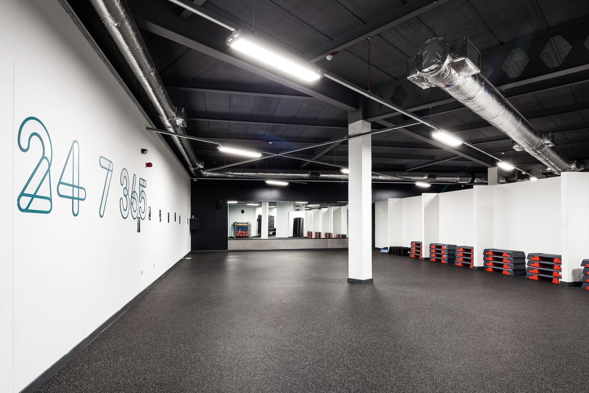 PureGym Manchester Stretford: Basement parking area with numbered spaces, ventilation ducts, and red lockers.
