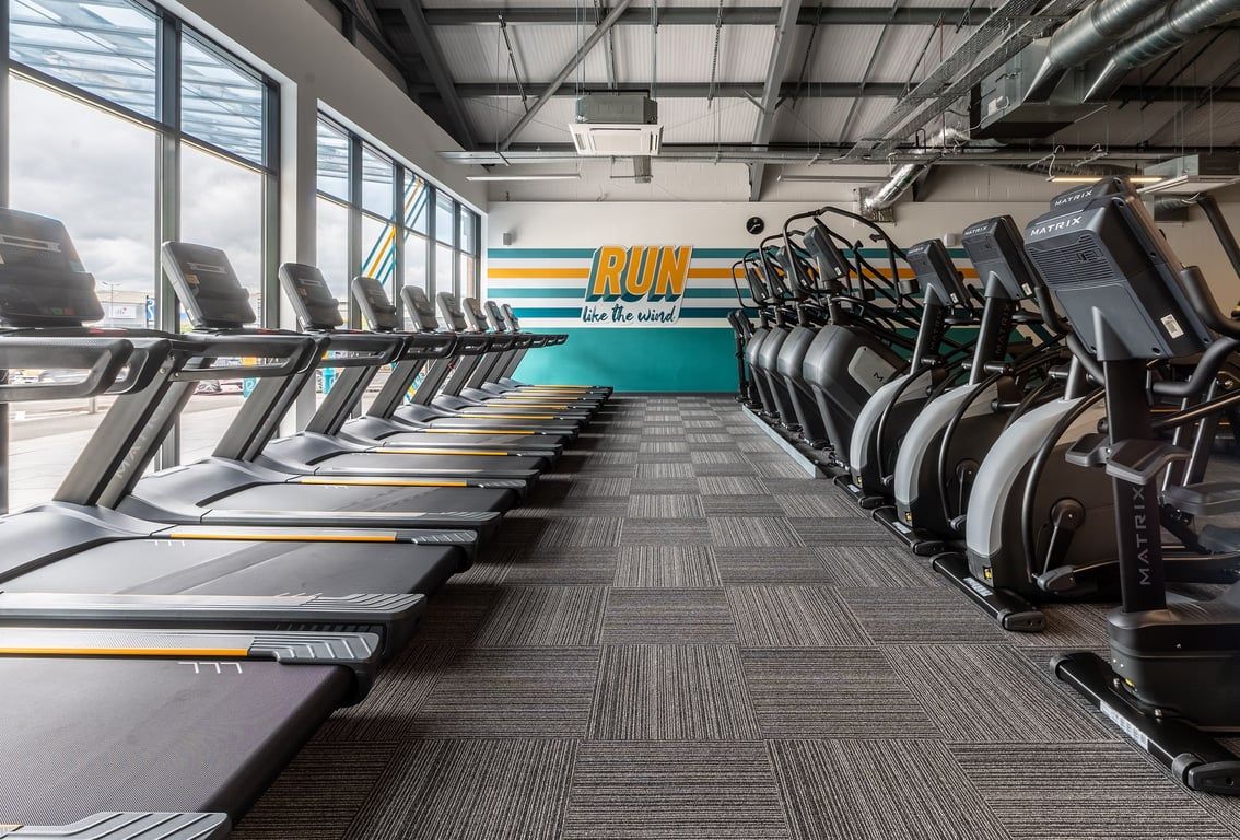 PureGym Derby Meteor Centre: Rows of treadmills, cross-trainers, and stationary bikes inside a brightly-lit fitness centre.
