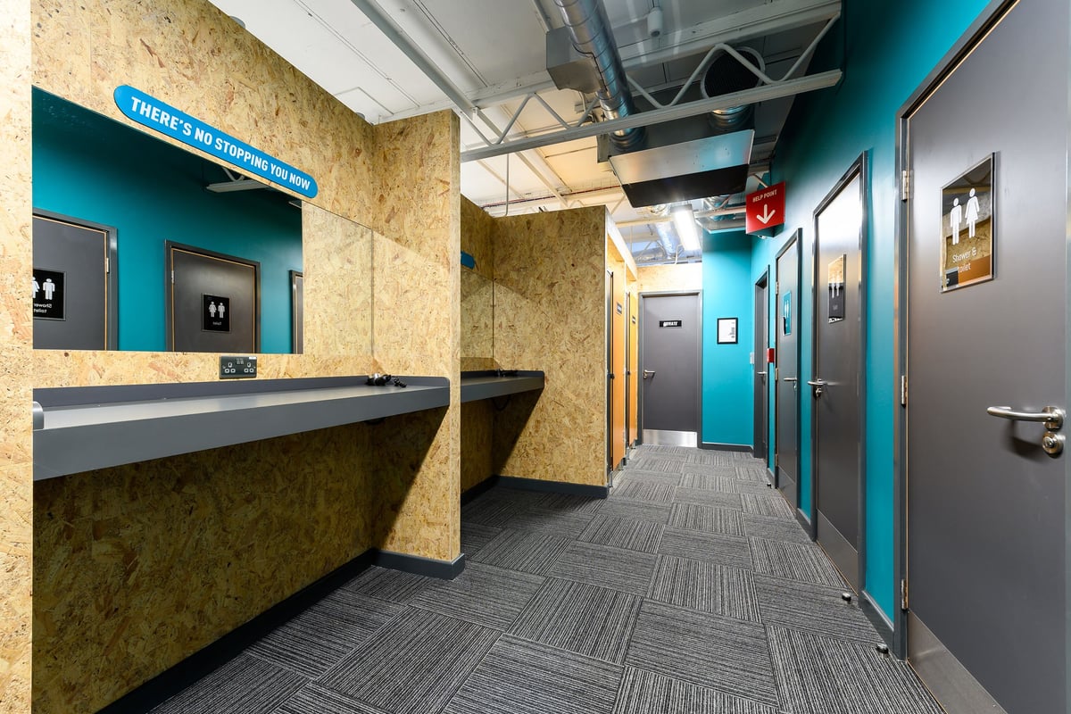 PureGym Didcot: Corridor with teal accents, sinks, hand dryers and changing cubicles.