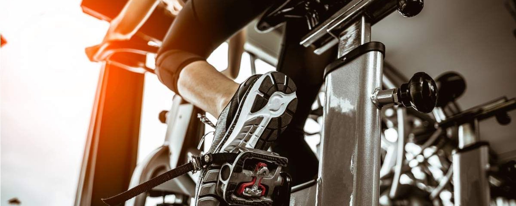 Personne pédalant sur un vélo d’appartement avec la lumière du soleil par la fenêtre