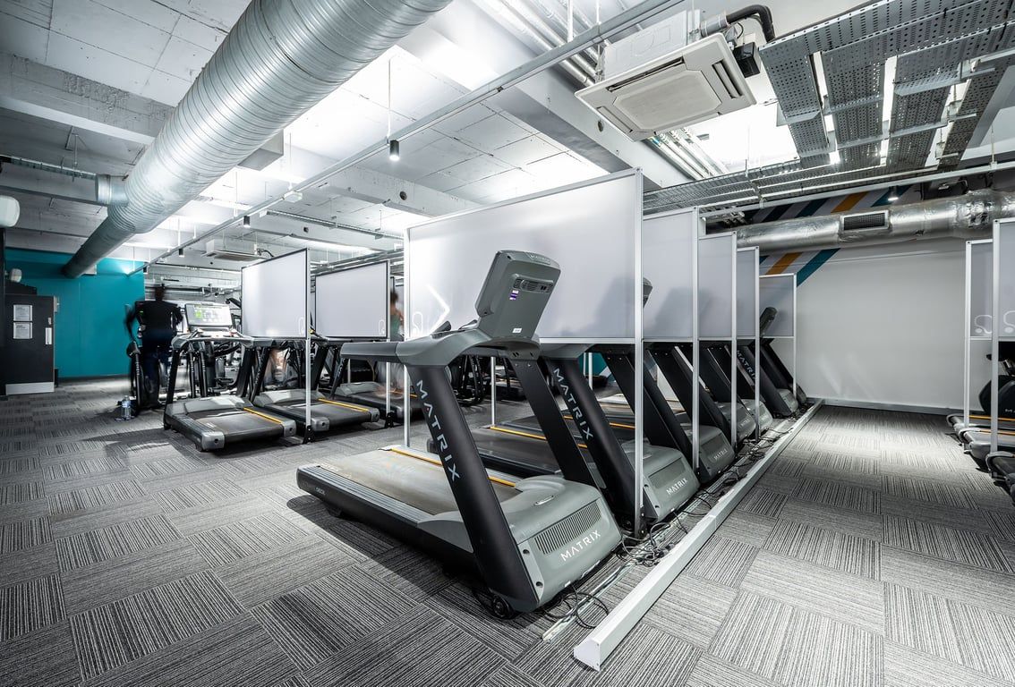 PureGym London Sydenham: Rows of treadmills, weight benches, and resistance machines in a sleek gym interior.