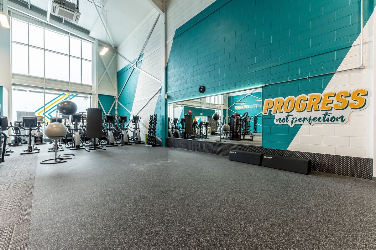PureGym Liverpool Edge Lane: Rows of stationary bikes, weight machines, benches, and a motivational wall mural.