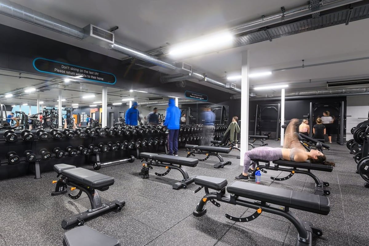 PureGym Bristol Abbey Wood Retail Park: Rows of weight benches, dumbbells, and strength training equipment in a well-lit gym.