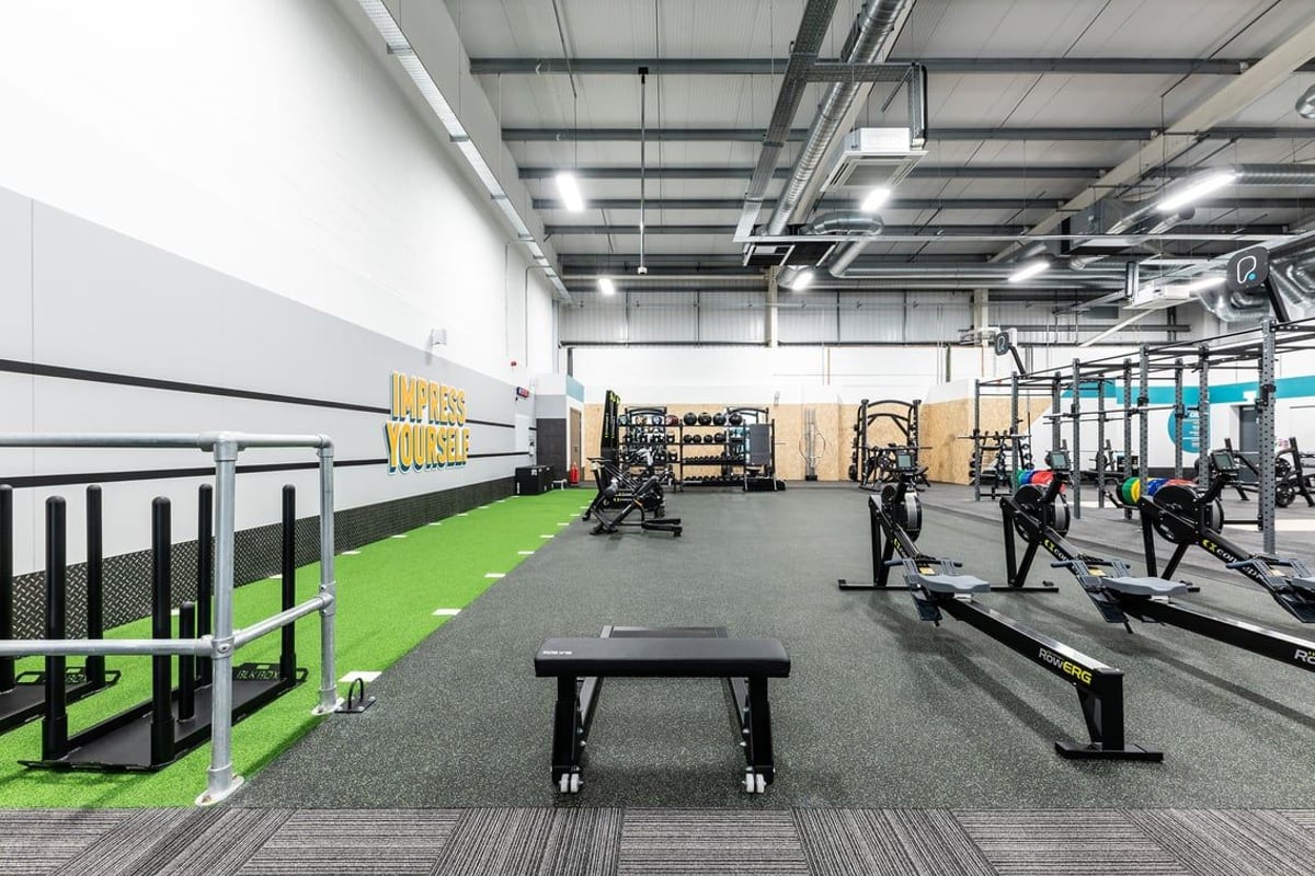 PureGym Great Yarmouth: Weightlifting area with squat racks, benches, turf section, and rubberized floors.