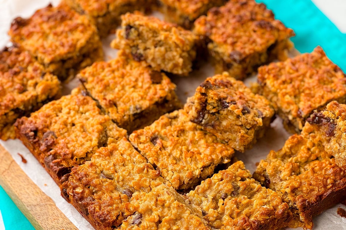 Golden baked oat and chocolate chip bars cut into squares on parchment paper
