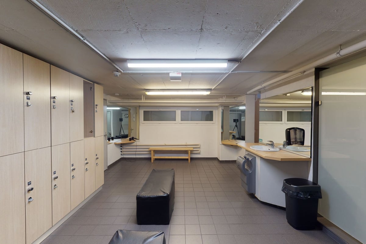 PureGym Basel Dreispitz: Lockers, benches, sinks, and tiled floors in a changing room.