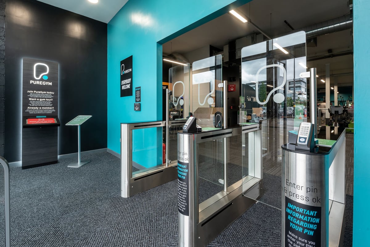 PureGym Birmingham Longbridge: Self-service kiosks, turnstiles, and signage for a gym or fitness centre.