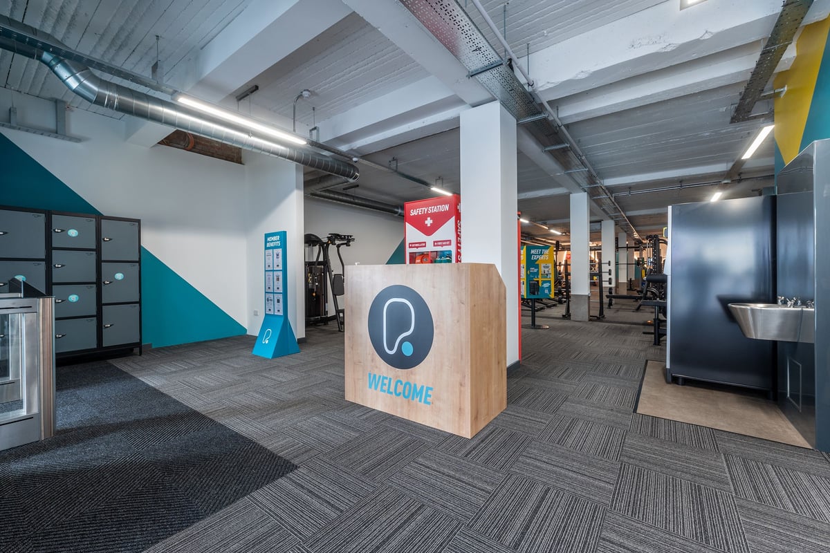 PureGym London Hornchurch: Reception area with exercise equipment, rubberized flooring, welcome sign.