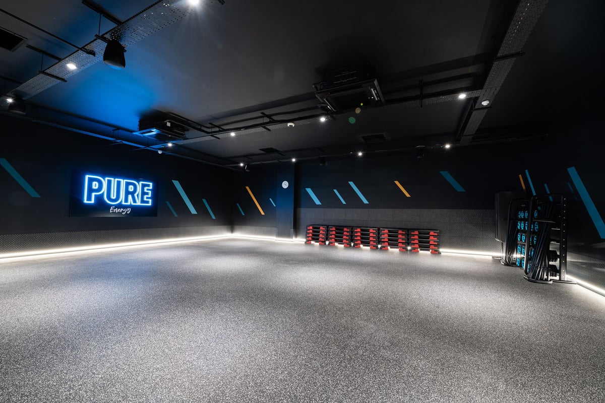 PureGym Dover: Red stadium-style seating, bright lighting, and a large PURE logo in an empty studio space.