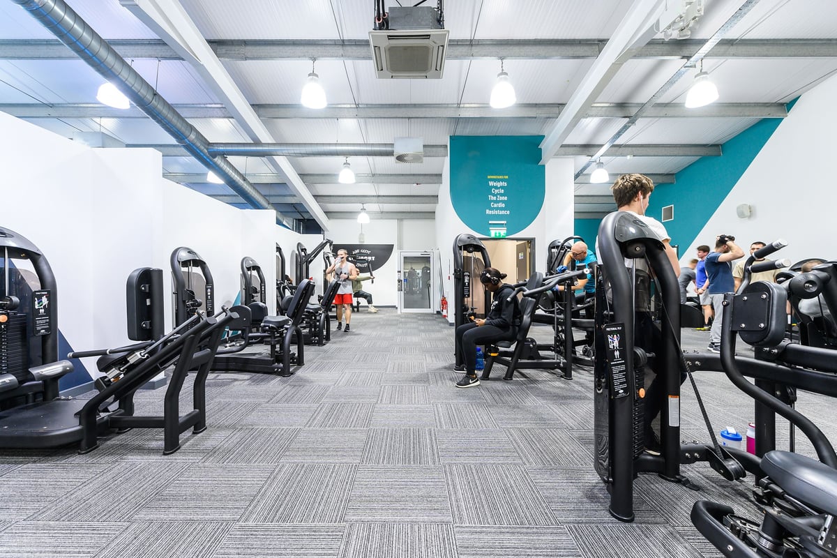 PureGym Oxford Templars Shopping Park: Rows of elliptical machines, treadmills, and weight stations in a modern gym setting.