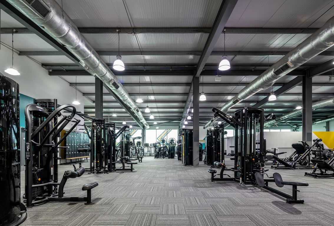 PureGym Cardiff Gate: Rows of weight machines, benches, free weights, and rubberized flooring in a gym setting.
