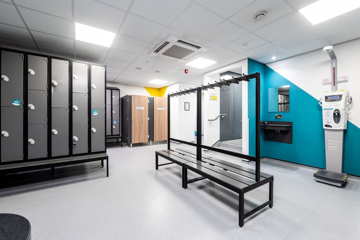 PureGym Wirral Bidston Moss: Lockers, benches, and shower cubicles in a changing room layout.