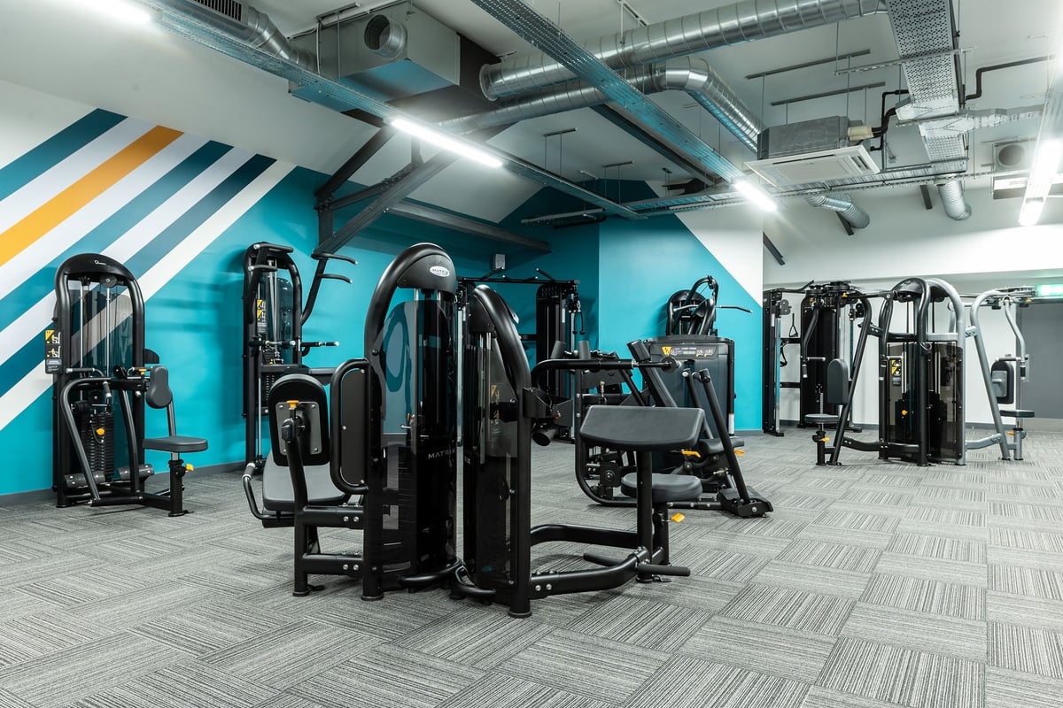PureGym London Streatham: Resistance training machines, weight stacks, and patterned flooring in teal-accented gym interior.