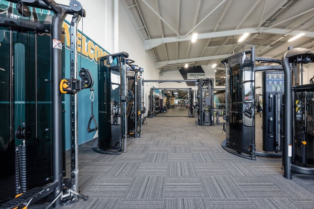 PureGym Falkirk: Rows of strength training machines, weights, and rubberized flooring in a spacious gym interior.