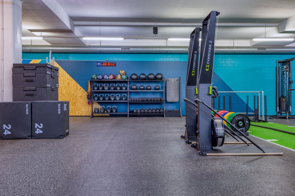 PureGym Dübendorf: A modern gym area with cardio equipment, weight racks, and a turf functional training zone.