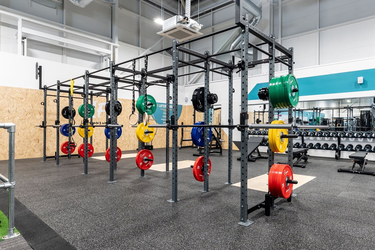 PureGym Durham City Retail Park: Racks with multi-colored weight plates, rubberized floors, rigs for functional training.
