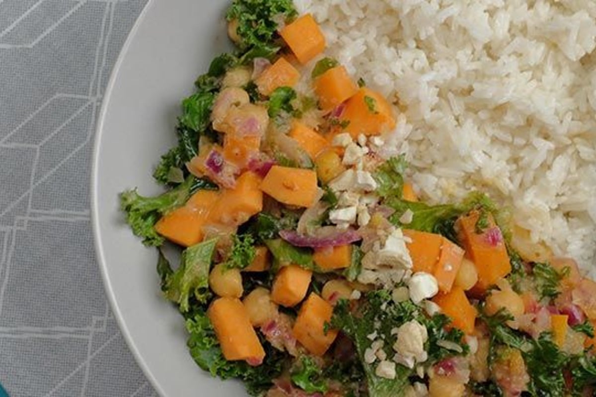Weißer Reis mit Grünkohl, Kichererbsen, gewürfeltem orangefarbenem Gemüse und zerbröckelte