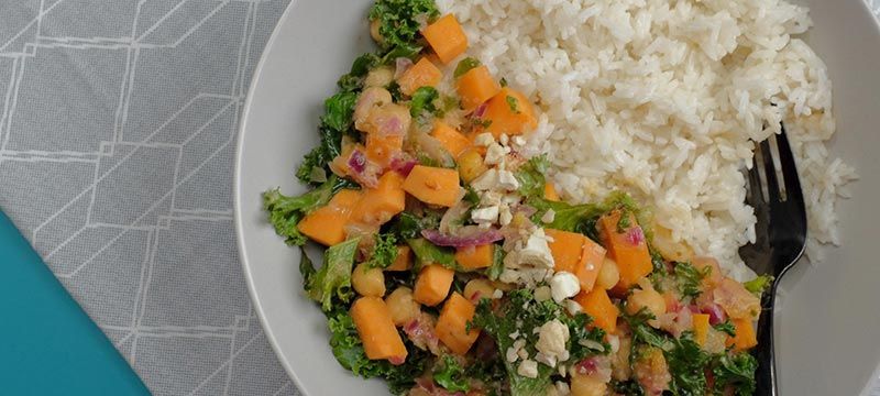 Weißer Reis mit Grünkohl, Kichererbsen, gewürfeltem orangefarbenem Gemüse und zerbröckelte