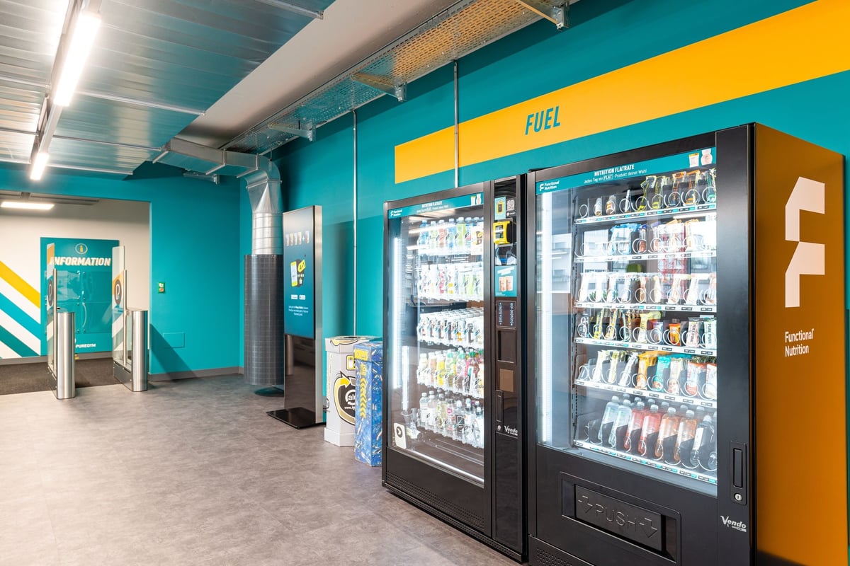 PureGym Altstetten: Blick ins Fitnessstudio mit Getränkekühlschränken und Snackautomaten in der Nähe der