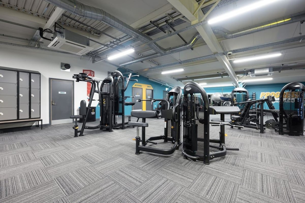 PureGym Falkirk: Weight machines, resistance equipment, rubberized patterned flooring in a gym setting.