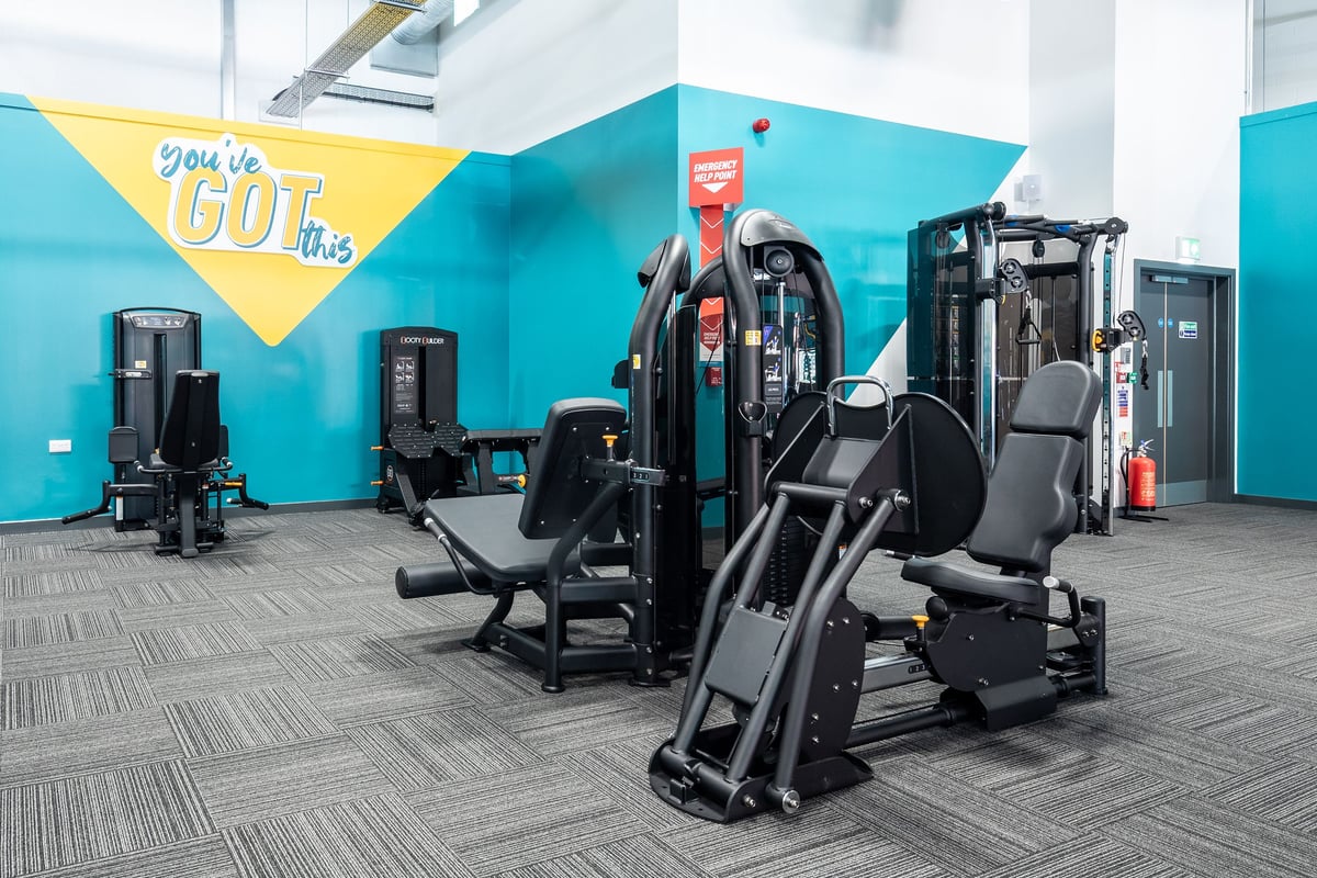 PureGym Ebbw Vale: Weight machines, exercise benches, and weight racks in a teal and yellow gym studio.