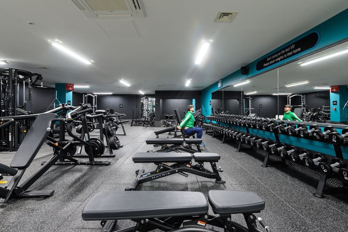 PureGym Didcot: Rows of weight benches, squat racks, free weights, and resistance machines in a dimly lit studio.