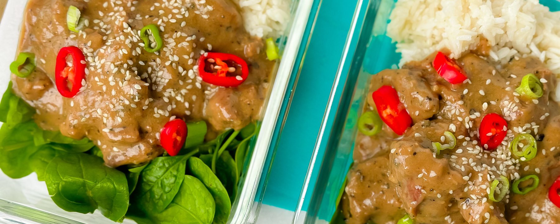 Two meal prep containers with glazed lamb, white rice, spinach, sesame seeds and chillies