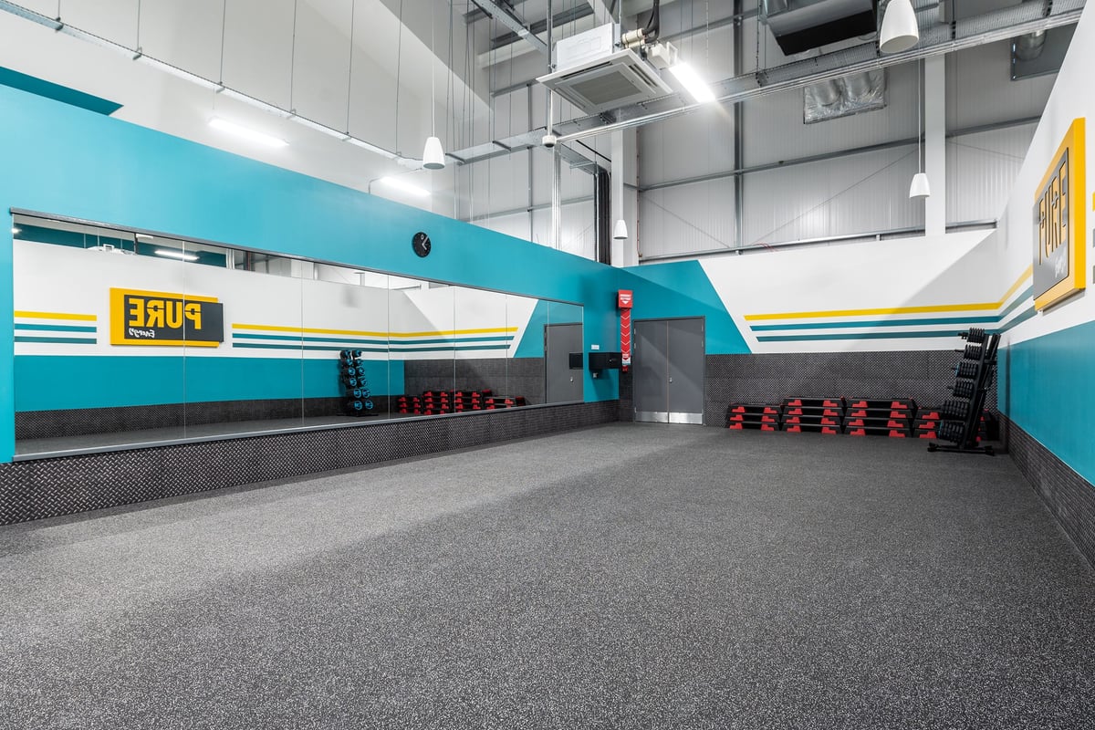 PureGym Alton: Resistance machines, free weights, rubberized flooring, and teal accented walls.