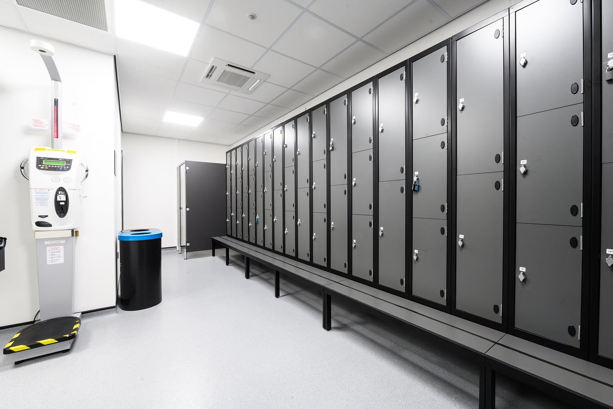 PureGym Burgess Hill: Rows of lockers, a water fountain and a trash can in a changing room area.
