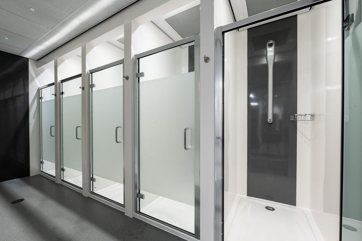 PureGym Cheshunt Brookfield Shopping Park: Glass-enclosed shower stalls with opaque doors and stainless steel hardware.
